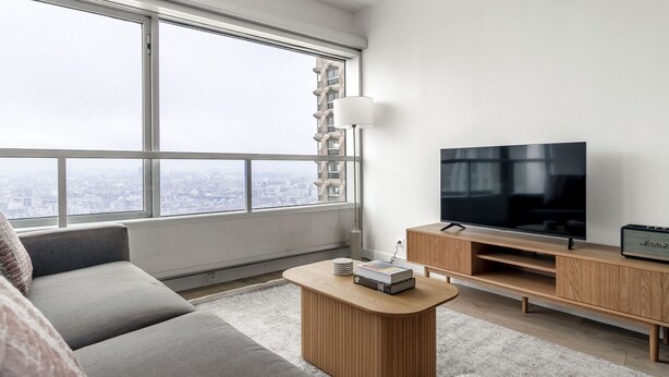A modern living room with a large window, a flat-screen TV, a wooden coffee table, and a grey sofa. - Blueground | La Motte-Picquet Grenelle, nr seine (Paris)