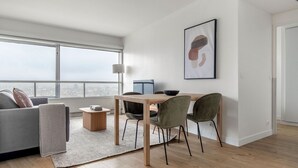A modern living room with a sofa, a dining table, and chairs. There is a large window with a view of a cityscape. - Blueground | La Motte-Picquet Grenelle, nr seine (Paris)