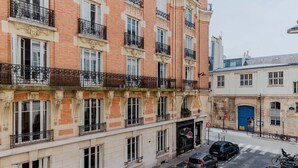 Un immeuble à plusieurs étages dont les façades sont faites d’un mélange de briques et de pierres, agrémenté de balcons décoratifs et de grandes fenêtres.