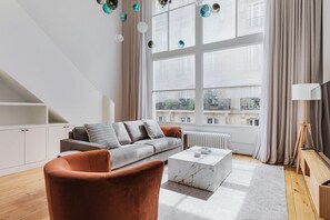 Una sala de estar moderna con un sofá gris, un sillón marrón y una mesa de centro de mármol.