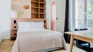 A modern bedroom with a bed, bedside tables, a built-in wardrobe, and a view of greenery through a window. - Blueground | Jardin des Plantes, furnished (Paris)
