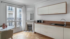 Una cucina compatta con pavimento in legno a spina di pesce, forno integrato e un'ampia finestra che si affaccia su un balcone.