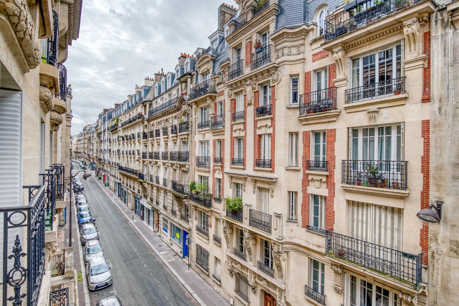 Una hilera de edificios históricos con balcones ornamentados y una calle en el medio.