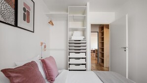 A bedroom with a bed, a closet with shelves, and a door leading to another room. - Blueground | Gibauderie, balcony, nr station (Paris)