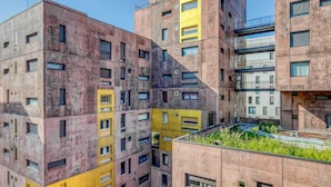 A multi-story building with a mix of pink and yellow facades, featuring a rooftop garden. - Blueground | Gibauderie, balcony, nr station (Paris)