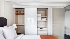 Une chambre à coucher comprenant un lit, une armoire avec espace pour suspendre les vêtements et une porte.