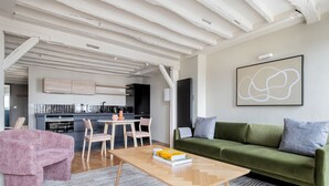Un salon moderne avec un canapé vert, une table basse en bois et un fauteuil rose.