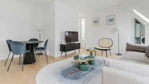 A modern living room with a dining area, a sofa, a TV, and a small side table. - Blueground | Les Halles, close to Eiffel Tower (Paris)