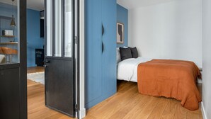 A bedroom with a bed, a blue wardrobe, a door, and a window. - Blueground | Porte Dauphine, near shops & food (Paris)