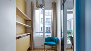 A modern apartment with a wooden floor, a teal armchair, and a view of the city through large windows. - Blueground | Porte Dauphine, near shops & food (Paris)