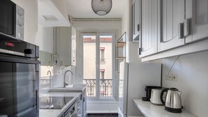 Een moderne keuken met een Bosch magnetron, spoelbak en roestvrijstalen apparatuur. Er is een balkon met uitzicht op de straat.