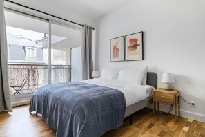 Relax in a serene bedroom with a large bed, wooden nightstand, and a balcony view.