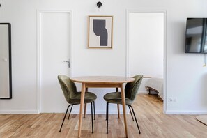 Relax in a stylish space with a round table, two comfortable chairs, and a mounted TV.