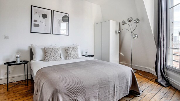 A modern bedroom with a large bed, a floor lamp, and abstract artwork on the wall. - Blueground | Jardin des Plantes, nr open markets (Paris)