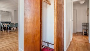 A room with a wooden door, a red bench, and a white wall with a mirror. - Blueground | Jardin des Plantes, nr open markets (Paris)