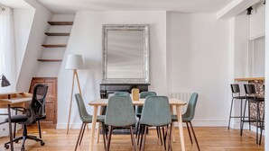 A dining area with a wooden table and chairs, a large mirror, and a staircase. - Blueground | Jardin des Plantes, nr open markets (Paris)