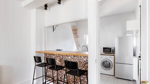 A compact kitchen with a washing machine, a microwave, and a refrigerator. - Blueground | Jardin des Plantes, nr open markets (Paris)