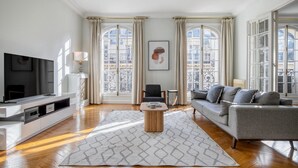 Un salon moderne avec un téléviseur à écran plat, un canapé gris et une table basse.