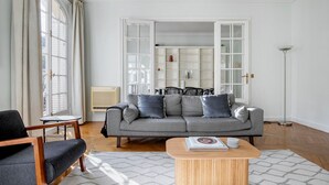 Un salon moderne avec un canapé gris, une table basse en bois et un fauteuil noir.