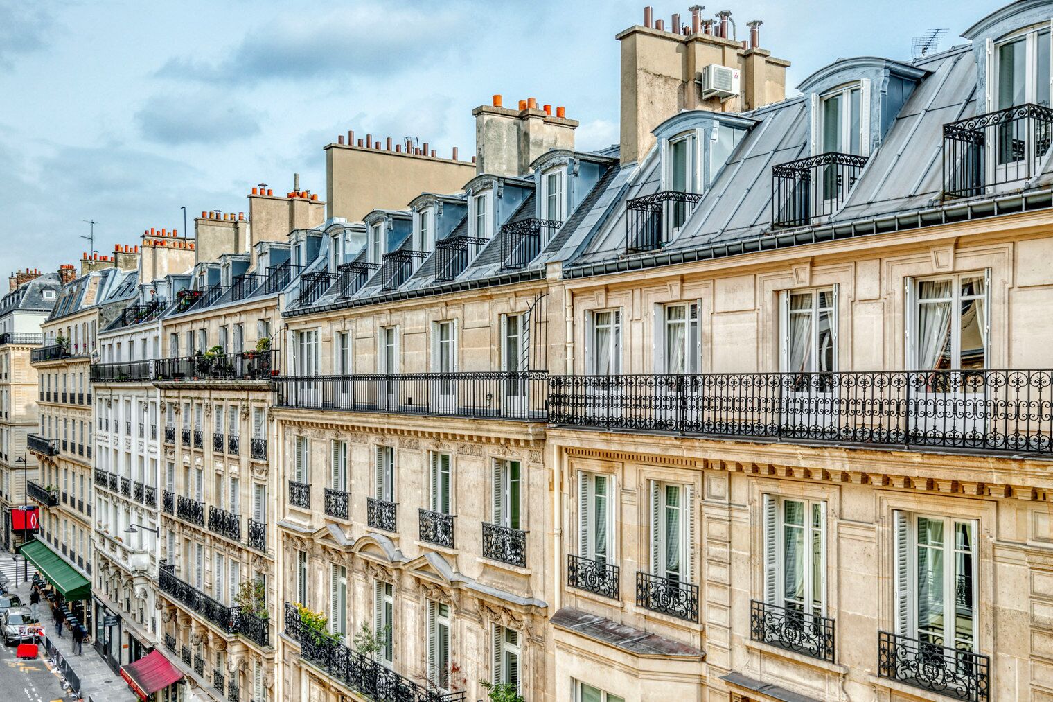 Eine Reihe klassischer europäischer Gebäude mit einheitlichem architektonischem Design, mit Balkonen und schmiedeeisernen Geländern sowie zahlreichen Fenstern mit Fensterläden.