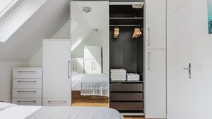 Et soveværelse med en seng, et skab og en garderobe med tøj.