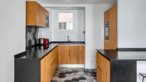 Una cocina moderna con armarios de madera, encimera negra y suelo de baldosas hexagonales.