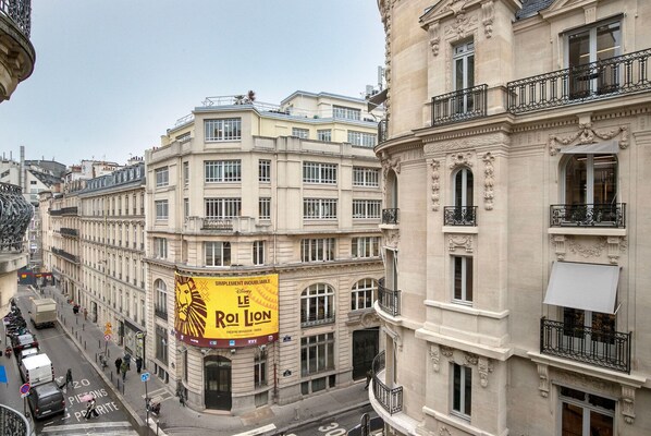A multi-story building with a prominent yellow banner advertising 'Le Roi Lion' at the ground level.