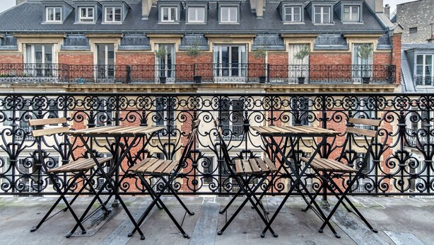 Eine Terrasse mit Sitzgelegenheiten und schmiedeeisernem Geländer.