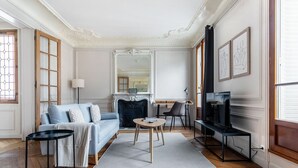 Ein Wohnzimmer mit Sofa, Couchtisch, Fernseher, Kamin und Kunstwerken an der Wand.