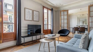 Ein Wohnzimmer mit Fernseher, Sofa und Essbereich.
