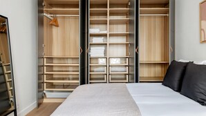 Ein Schlafzimmer mit einem großen Bett, einem Schrank mit zahlreichen Fächern und einem Spiegel.