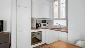 Eine kleine Küche mit weißen Schränken, einer Holz Arbeitsplatte, einem eingebauten Backofen, einer Mikrowelle und einem Fenster mit Blick.
