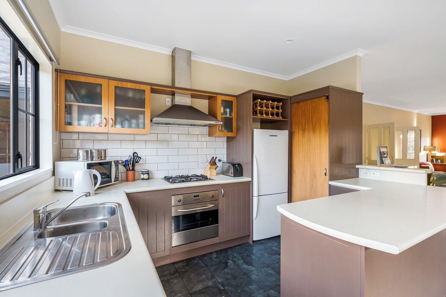 Une cuisine moderne dotée d’un îlot central, d’appareils électroménagers en acier inoxydable et de meubles de rangement en bois.