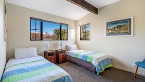 A bedroom with two beds, a window with a mountain view, a framed painting, and a chair. - Criffel Peak Cottage, quiet location, only 10 min walk into Wanaka town centre (Wānaka)