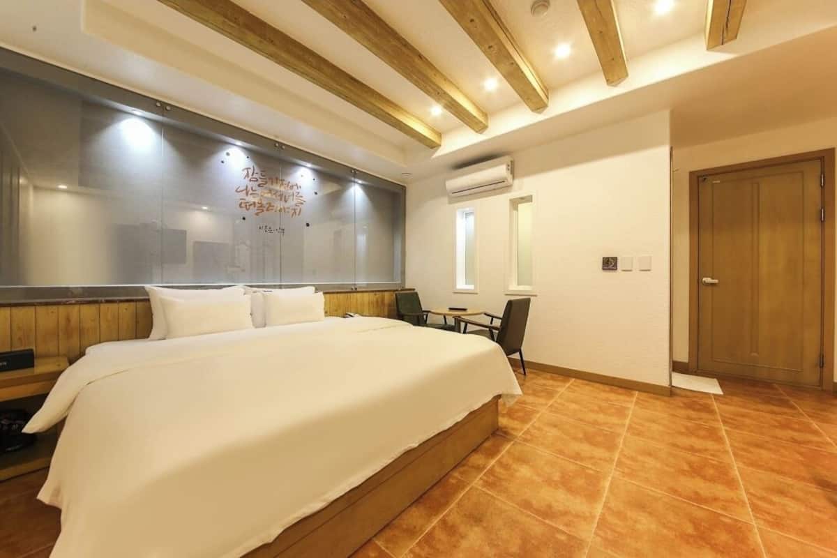 Una habitación de hotel con una cama grande, cabecero de madera, un escritorio pequeño y una puerta.
