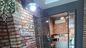 A modern interior with a brick wall, a welcome sign, and a sign indicating the establishment is open. - Pyeongtaek Station Gallery Hotel (Pyeongtaek)