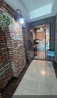 Un interior moderno con una pared de ladrillo, un cartel de bienvenida y una señal que indica que el establecimiento está abierto.