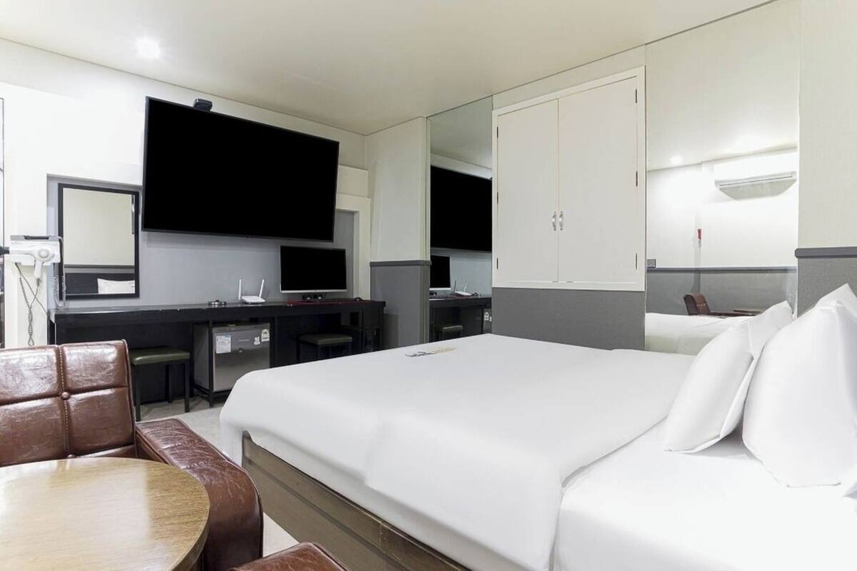 Una habitación de hotel con cama, escritorio, silla, televisor y armario.