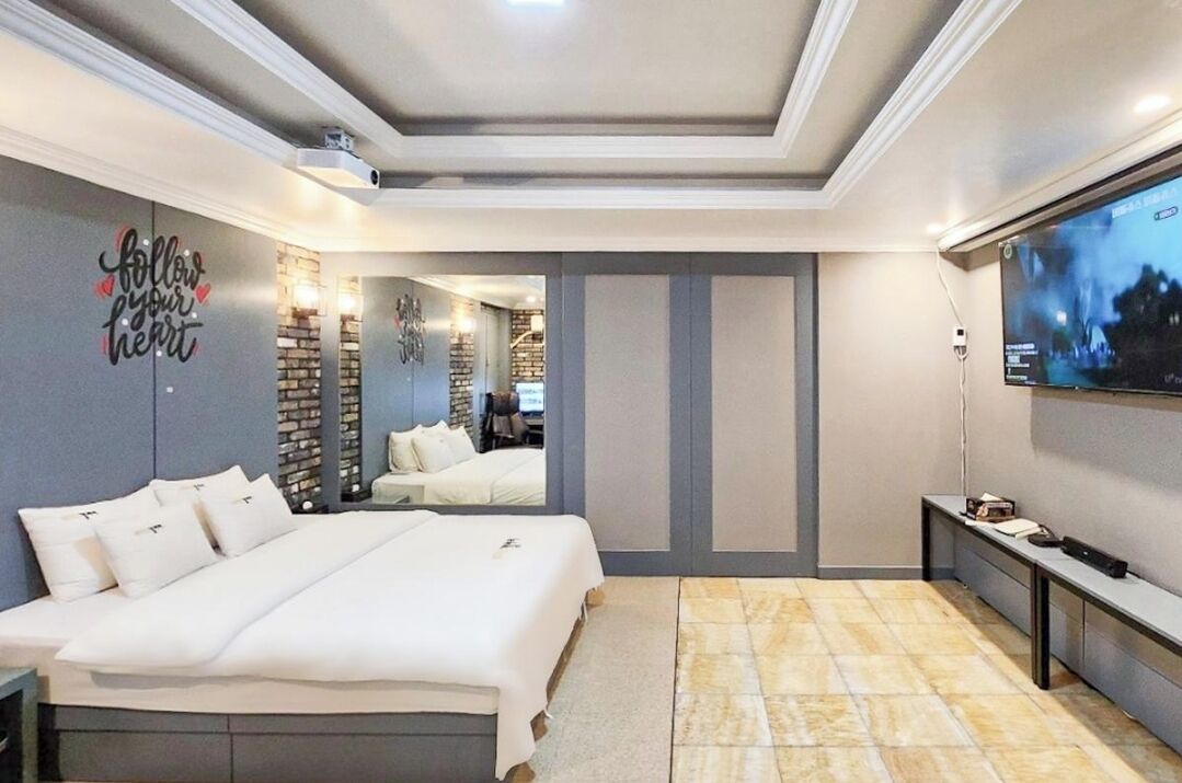 Een moderne slaapkamer met een groot bed, een televisie en een spiegel.
