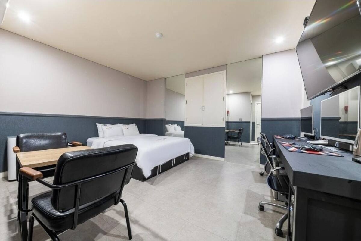Una habitación de hotel con cama, escritorio, silla, televisor y armario.
