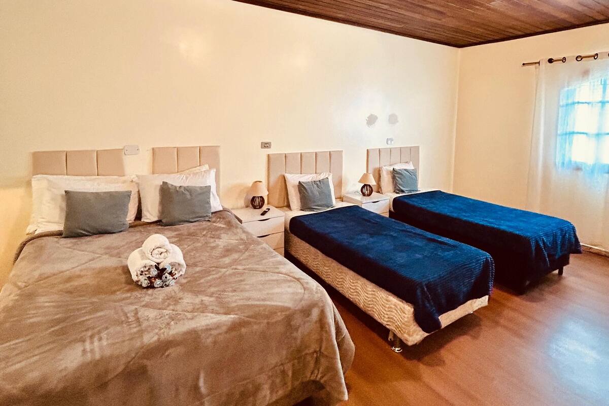 A hotel room with two beds, wooden ceiling, and a window with curtains.