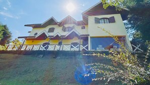 Une maison à plusieurs étages, dotée d’un toit en pente, d’un garage apparent et d’une cour clôturée.