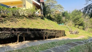 Un bâtiment jaune doté d’un balcon, d’un chemin pavé et d’une zone herbeuse avec un banc.