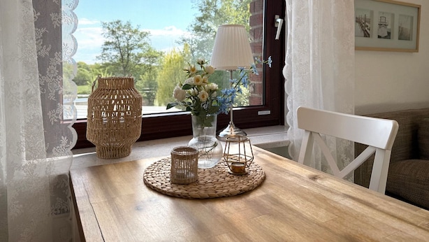 Ein Holztisch mit gewebten Tischsets, einer Blumenvase und einer Lampe.