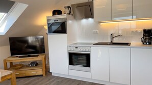 Eine kompakte Küche mit integriertem Backofen, Mikrowelle und Kaffeemaschine.