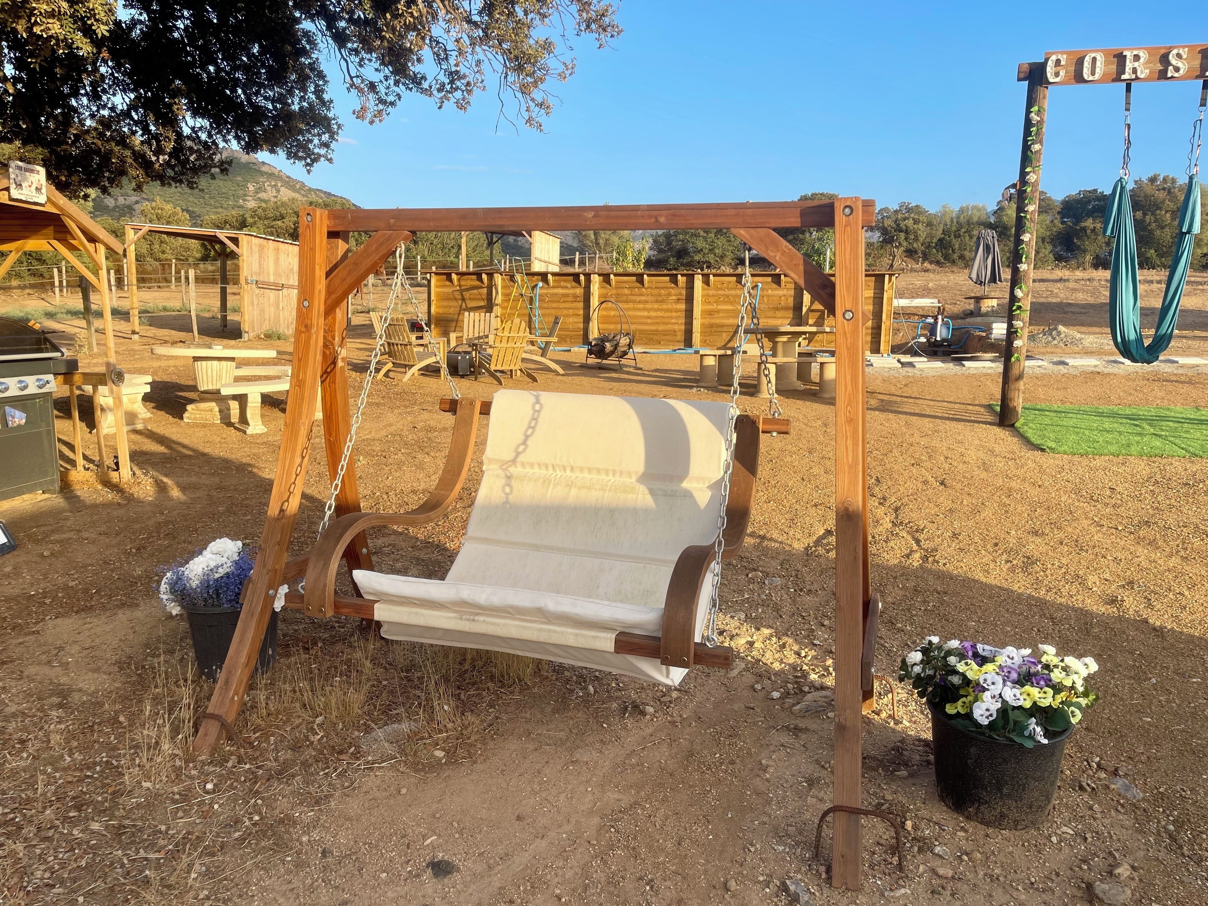 Un tobogan de fusta en una zona àmplia i seca, amb taules de picnic i un senyal que diu "CORS".