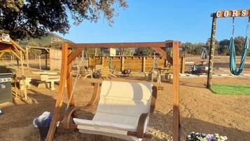 Un tobogan de fusta en una zona àmplia i seca, amb taules de picnic i un senyal que diu "CORS".
