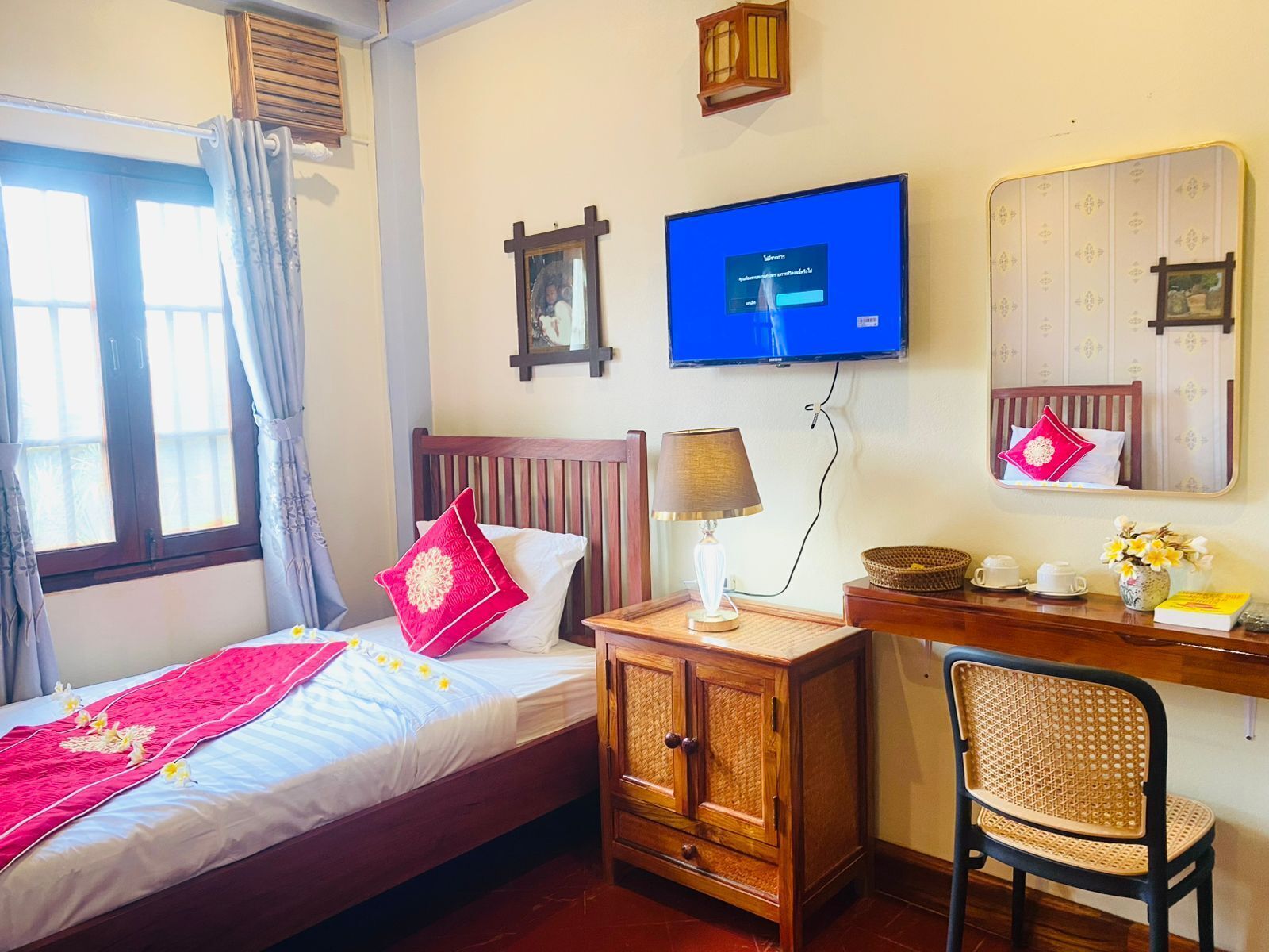 A hotel room with a bed, a desk with a lamp, a chair, a television, and a mirror.