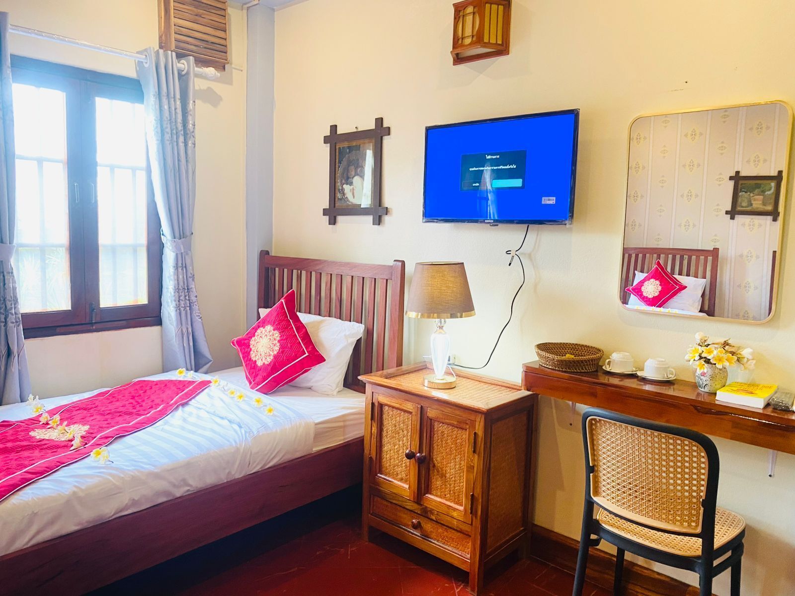 Habitació d'hotel amb un llit, un escriptori amb una cadira, una televisió i un mirall.