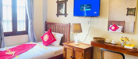 Habitació d'hotel amb un llit, un escriptori amb una cadira, una televisió i un mirall.